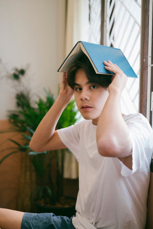 Short hair guy in casual look drop the book on his head at the window.の写真素材