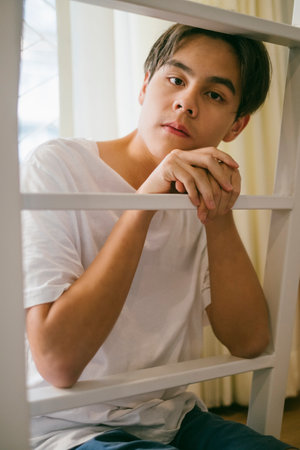 Black hair guy in white t-shirt grab the ladder and prop his chin on the ladder.の写真素材