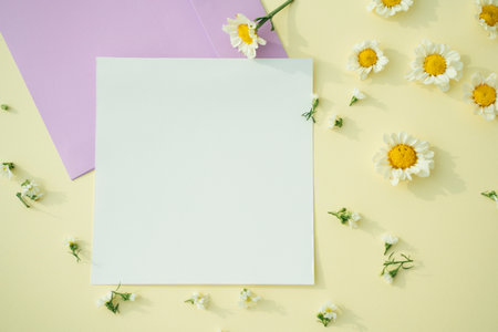 White mock up paper with flower over yellow background. Top view.の写真素材