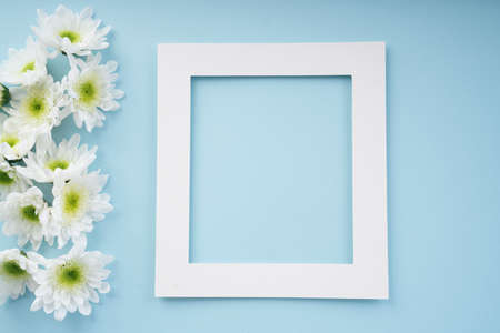 Mock up white frame with flower over bright blue background. Blooming season concept.の写真素材