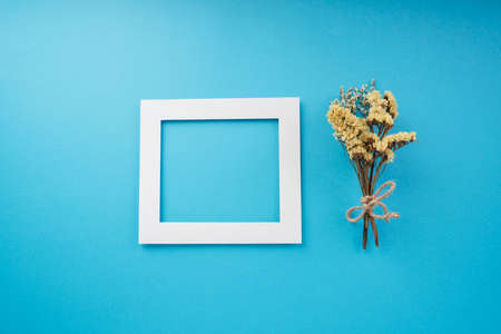 White frame mock up and yellow flower bouquet over bright blue background. Top view.の写真素材