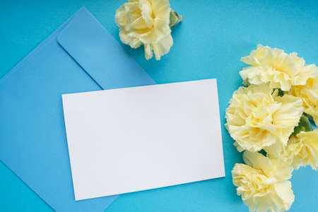Top view - White paper mock up and blue enclosed letter with yellow flower.の写真素材