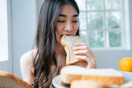 long hair girl in her house eat Breakfast bread , lookingの写真素材