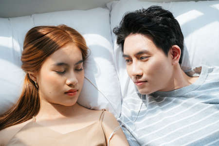 Lover lie down on the bed together in the morning, a man look at a woman while she sleeep.の写真素材
