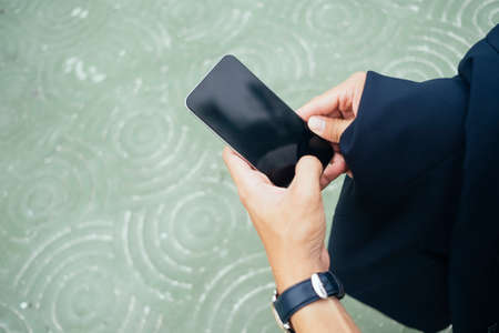 Cropped image of smartphone in man's hand on the green floor.の写真素材