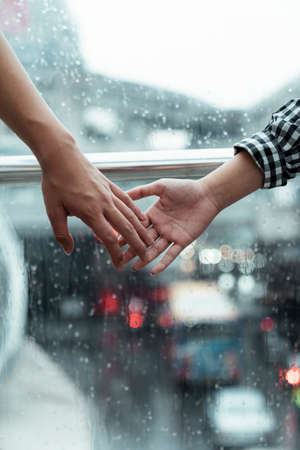 Close up shot of couple's hands that going to hold each other in rainy day.の写真素材