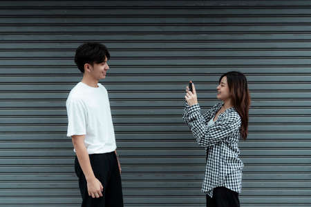 A girl in black and white plaid take a photo for her boyfriend at shutter door.の写真素材