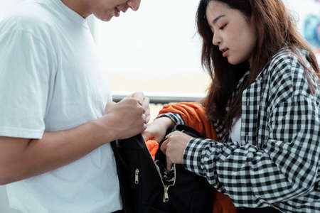 Teenage couple find the wallet in the black backpack together.の写真素材