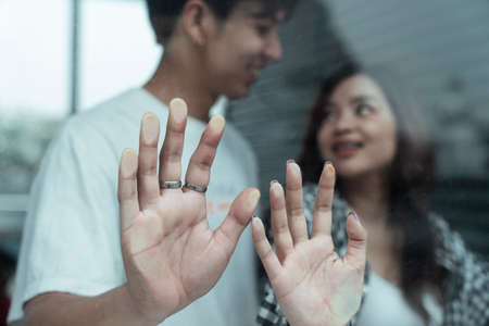 Close up shot of teenager couple's hands touching the glass while they enjoy something at front.の写真素材