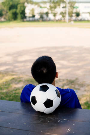 A boy sitting on a stand with a ball as a pillow and sleep.の写真素材