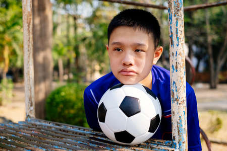 A boy in blue football suit prop his head on a ball on the climb frame.の写真素材