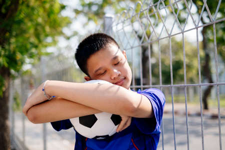 A buy hug his beloved football and snnuggling up to it. Little boy express his love by hugging the football.の写真素材