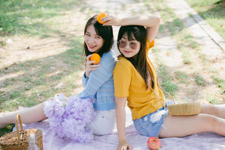 Two girls sitting on the mat on the floor holding the orange and play.の写真素材
