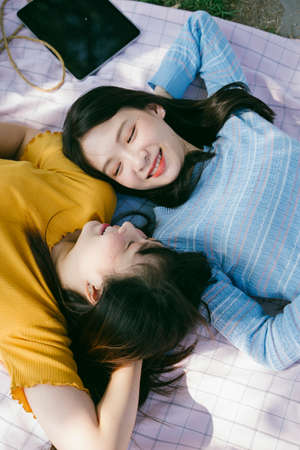 Two girl lie down on the mat listen the music and use the tablet.の写真素材