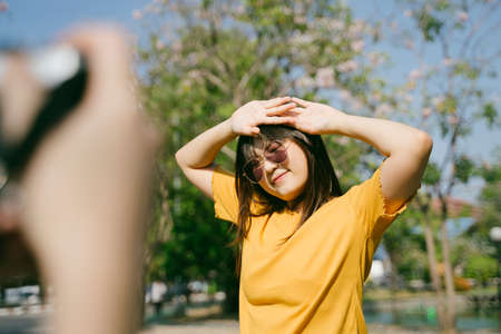 Long hair girl standing in the sunlight with sunglasses to take a photo.の写真素材
