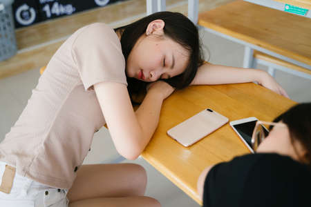 Long hair girl sleep at the bench in the laundromat while waiting for her clothes.の写真素材