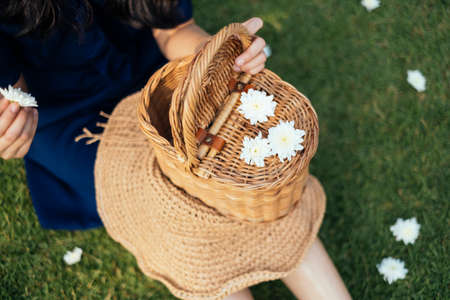 Close up shot of a wooden basket and white flower on the woman's legs in a field.の写真素材