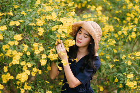 Curly long hair girl wear brown hat enjoy with yellow flower.の写真素材