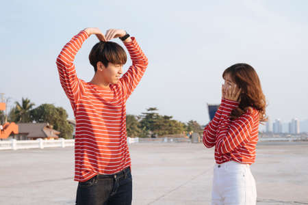 A guy in red t-shirt make a big heart over his head with his arms.の写真素材