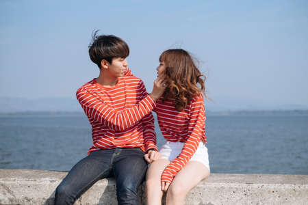 Black hait guy grab his girlfriend's face while she squeeze his cheek, horizontal.