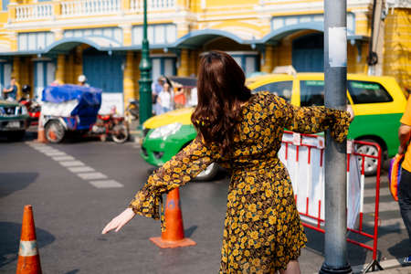 Cute curly long hair girl in yellow dress grab the pole sign and spread another arm next to the red...