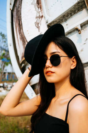 Portrait photo of black long hair girl in spaghetti strap and pink skirt in front of wreck plane.の写真素材