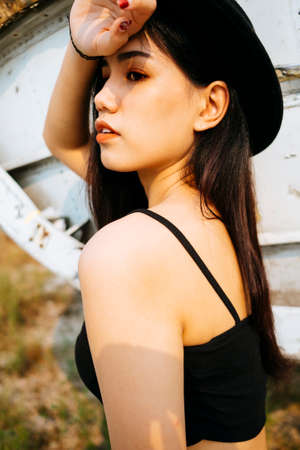 Black long hair girl in spaghetti strap standing in front of wreck plane and raise her arm at forehead.の写真素材