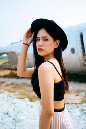 Black long hair girl in black spaghetti strap and pink skirt standing in the abandoned area with ruin plane.の写真素材