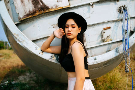 Black long hair girl in spaghetti strap standing in front of wreck plane and raise her arm at...