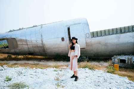 Black long hair girl wearing the gorgeous clothes and pink suit with black hat standing at the ruin plane in the abandoned area.の写真素材