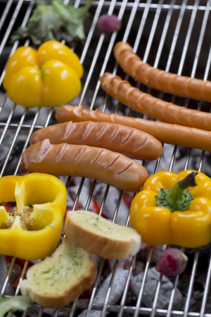 Fresh sausage and hot dogs grilling outdoors on a gas barbecue grill.の写真素材