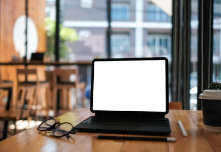Front view blank screen tablet which on wooden table in coffee cafe.の写真素材