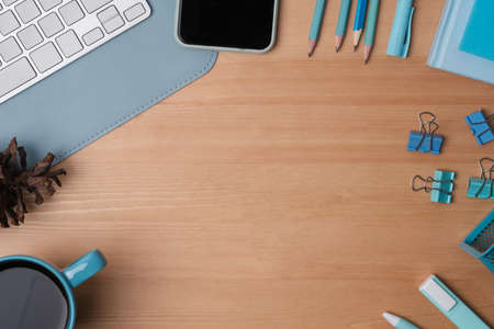 Top view of office wooden table with mobile phone, coffee cup and stationery equipments.の写真素材