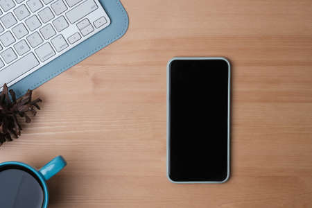 Top view of office desk with mobile phone and coffee cup on wooden background