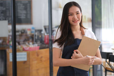 Female entrepreneur of SME coffee shop hold chart board and standing with cafe background, Business...