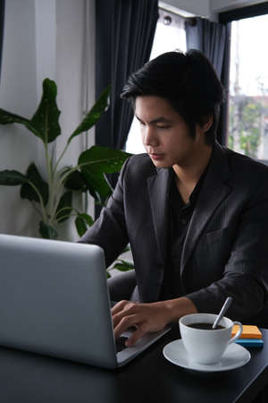 Portrait with Asian businessman using laptop computer in office.