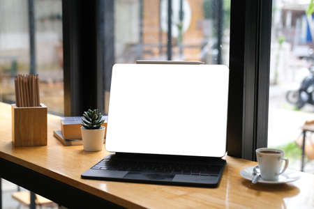 Mockup and closed view with white screen of tablet with stylus pen on top and espresso coffee beside, all place on wooden table.の写真素材