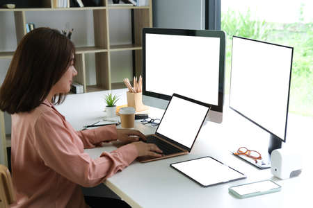 Female programmer working with laptop, two computers and tablet, blank screen of devices, Programmer...
