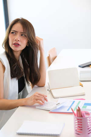 A serious young woman sitting in office room while analysis with documents.の写真素材