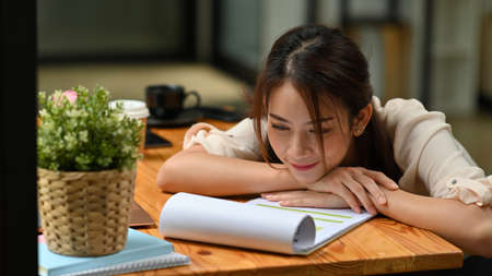 Portrait with Asian woman slum on wooden table and reading a paper.の写真素材