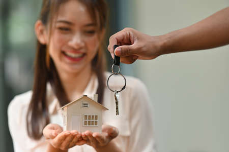Closed up with male hand giving a keys and female hold house model in her hands, Mortgage loan approval home loan and insurance concept.の写真素材