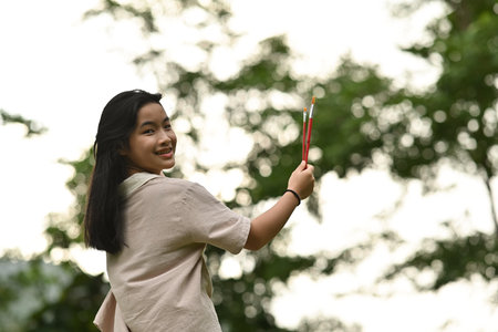Portrait with little girl hold paint brush in her hand and look backward on the camera.の写真素材