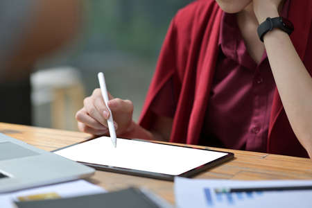 Closed up with Asian female in red shirt and overcoat using stylus pen white on display of tablet, white screen of tablet.の写真素材