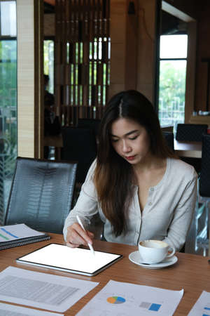 Portrait with businesswoman using stylus pen and tablet for working and analyze data paper on wooden table.の写真素材