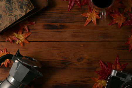 Mock up and top view with wooden table decorated by Moka pot, camera, maple leaves, black coffee and old books.の写真素材