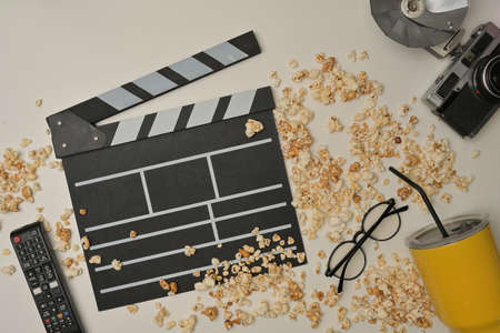 Above view with popcorn spilled on the table and clapper board, remote, eyeglasses, vintage camera and yellow glass decorated.の写真素材