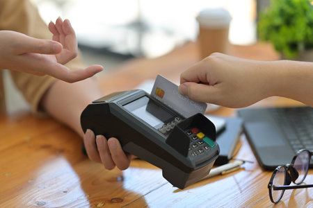 Closed up and cropped view with customer paying with contactless credit card.