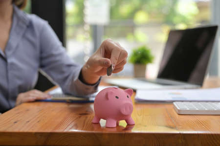 Closed up with women putting coin in piggy bank, saving money concept.の写真素材