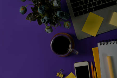 Top view and mock up with a cup of coffee on purple desk with laptop and smartphone.