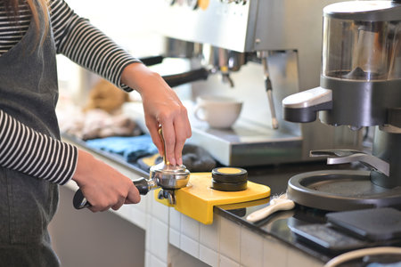 Closed up with professional female barista hand make a coffee with coffee tamper in restaurant pub...